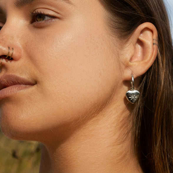 Silver heart charm earrings with starburst detail