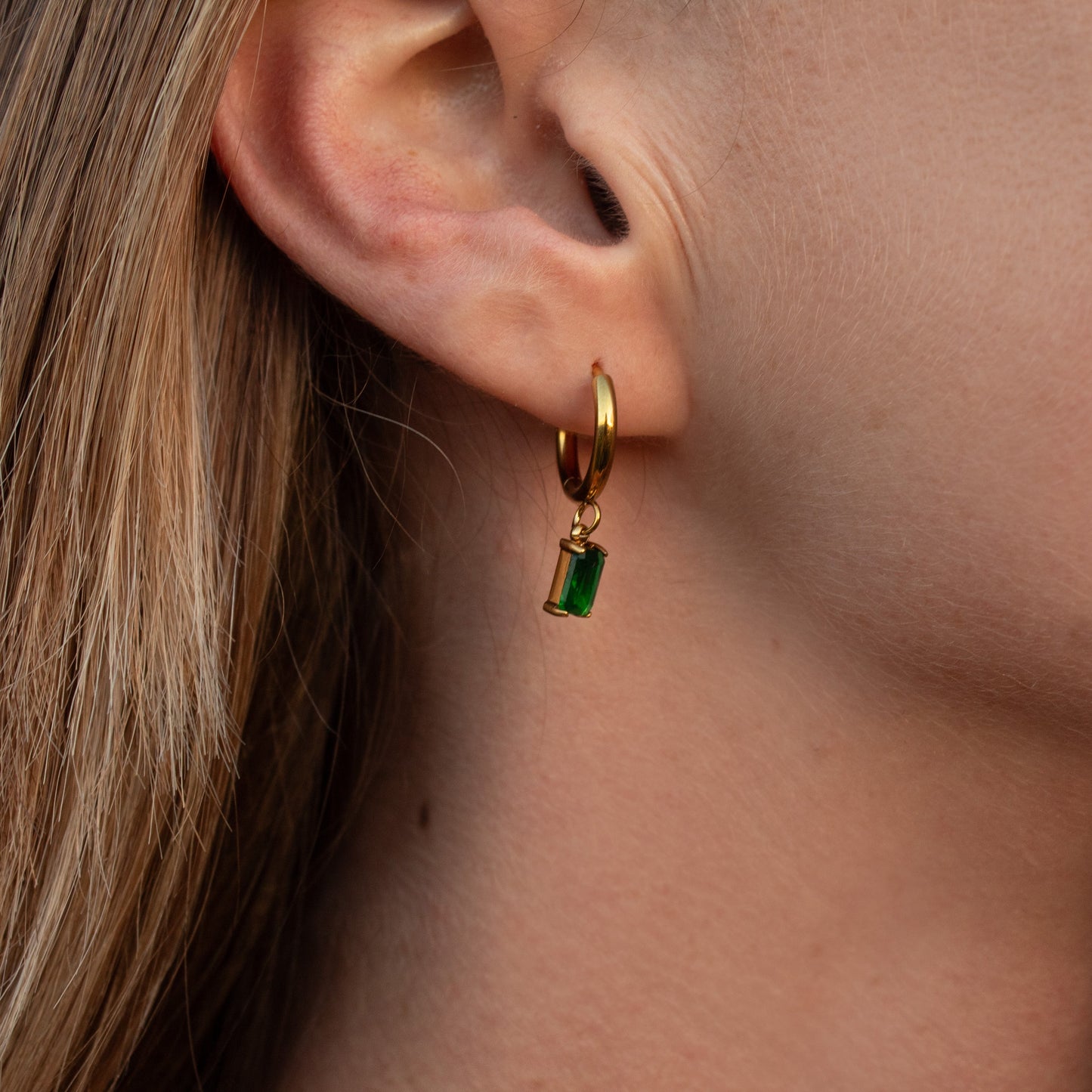 Gold hoop earrings with green emerald charm