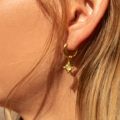Gold hoop earrings with starburst charm and gemstone