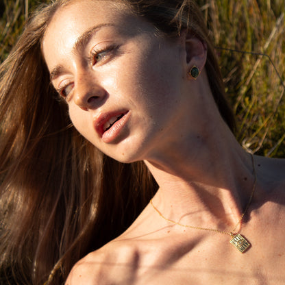 Woman with long blonde hair wearing gold pendant necklace