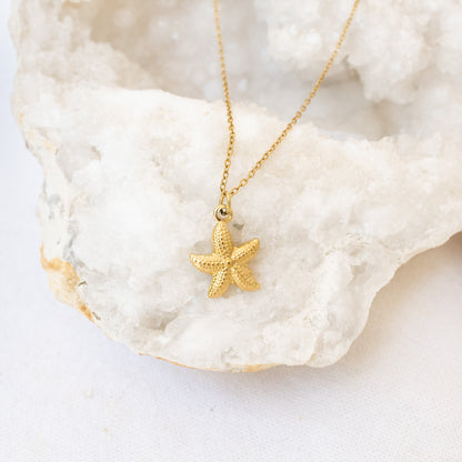 Gold starfish necklace on white geode